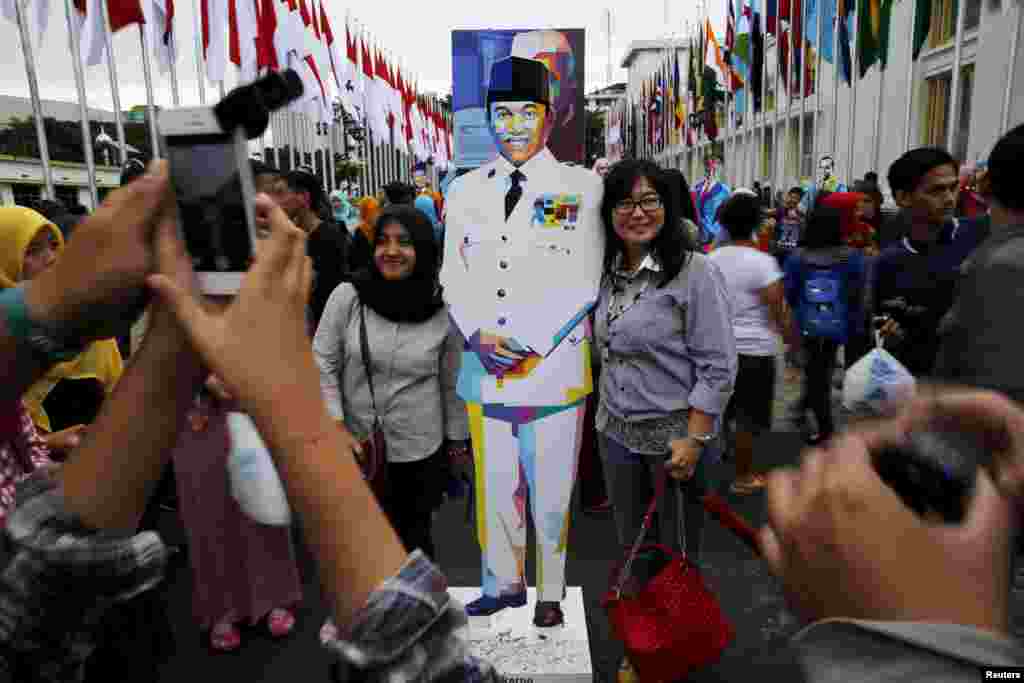 People pose for pictures with a statue of Indonesia's first president Soekarno in Bandung, Indonesia, April 24, 2015. 