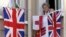 FILE - A woman resident of Gibraltar looks out of a window behind flags of England and Gibraltar, Aug. 4, 2004. For British-ruled Gibraltarians, London's membership in the EU prodives a safety net they would lose if Britain were to exit the EU.