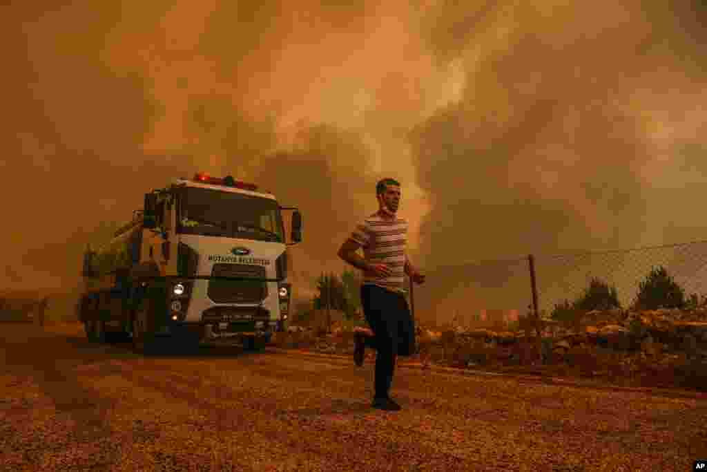 A man runs in the fire-devastating Sirtkoy village, near Manavgat, Antalya, Turkey. More than 100 wildfires have been brought under control in Turkey, according to officials.