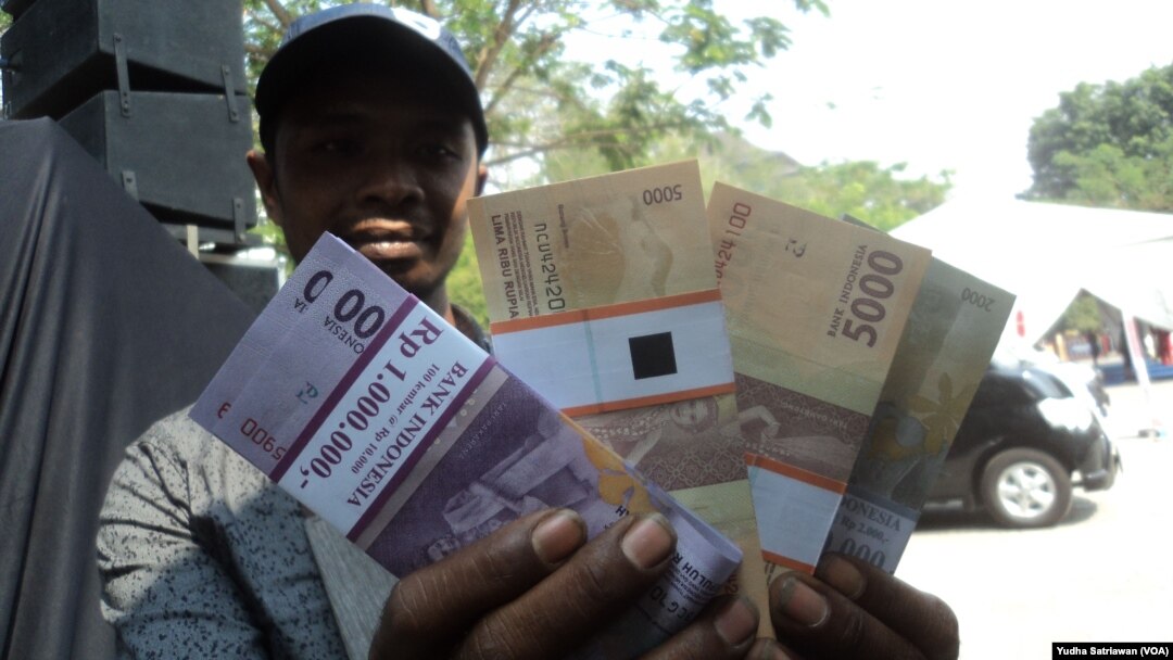 Seorang warga menunjukkan uang tunai lembaran baru hasil penukaran di mobil perbankan Solo, Solo, 5 Juni 2018. (Foto: Yudha Satriawan)