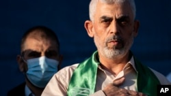 Yahya Sinwar, pemimpin Hamas Palestina di Jalur Gaza, meletakkan tangannya di dada di atas panggung setelah menyapa para pendukungnya dalam sebuah unjuk rasa pada 24 Mei 2021, di Kota Gaza, Jalur Gaza. (Foto: AP)