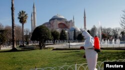 FILE - A worker in a protective suit disinfects Sultanahmet square, with Hagia Sophia in the background, in response to the spread of coronavirus disease (COVID-19) in Istanbul,Turkey, March 21, 2020.
