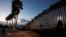 People walk along the U.S. border wall in an oceanside park in Tijuana, Mexico, at sunset, Nov. 30, 2018. 