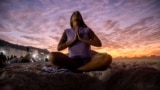 FILE - A woman sits in lotus prayer pose during the "Yoga at the Sunrise" event on Copacabana beach, in Rio de Janeiro, on June 22, 2024. (AP Photo/Bruna Prado)