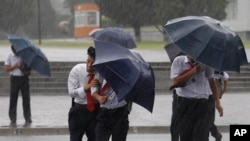 Pedestrians shield themselves from wind and rain brought by Typhoon Lingling Saturday, Sept. 7, 2019, in Pyongyang, North Korea.