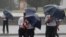 Pedestrians shield themselves from wind and rain brought by Typhoon Lingling Saturday, Sept. 7, 2019, in Pyongyang, North Korea.