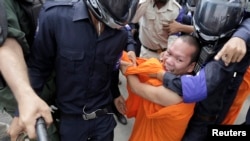 Cambodian police detain a Buddhist monk who was seeking the release of seven convicted land-rights activists in Phnom Penh, Nov. 11, 2014.