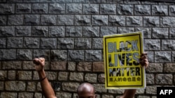 FILE - A protester holds a Black Lives Matter sign outside the U.S. consulate during a demonstration against racism and police brutality in Hong Kong, June 7, 2020.