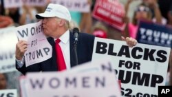 Kandidat presiden AS dari partai Republik, Donald Trump, mencium kertas bertuliskan "Perempuan untuk Trump" dalam kampanye di Lakeland, Florida (12/10). (AP/Evan Vucci)