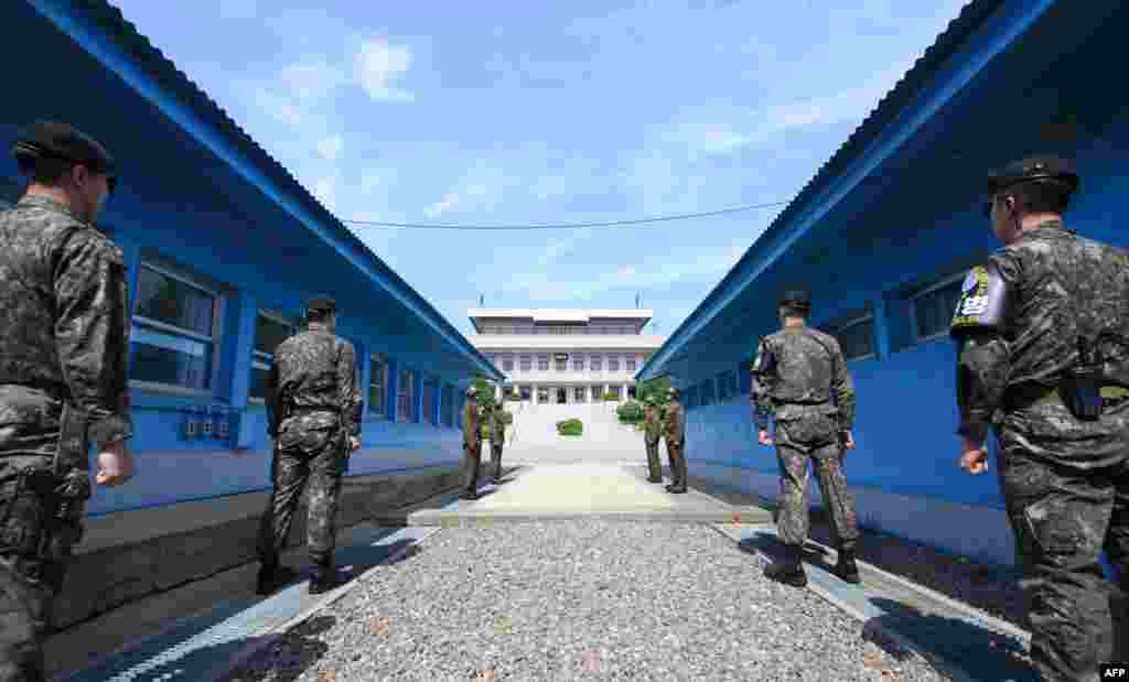 South Korean soldiers (front) and North Korean soldiers (rear) stand guard before the military demarcation line on the each side of the truce village of Panmunjom in the Demilitarized zone (DMZ) dividing the two Koreas.