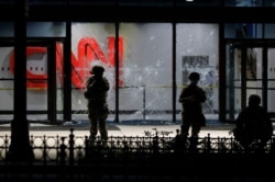 Members of the Georgia National Guard stand in front of shattered glass at the CNN Center in the aftermath of a demonstration against police violence, May 30, 2020, in Atlanta.