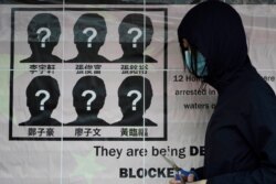 FILE - A university student puts up a poster to demand the release of the 12 Hong Kong activists detained at sea by Chinese authorities, at a "Lennon wall" in the University of Hong Kong, Sept. 29, 2020.