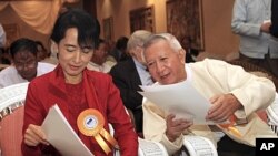 Burmese pro-democracy leader Aung San Suu Kyi and President's Economic Adviser U Myint read documents during a workshop on the development in Rangoon, November 7, 2011.