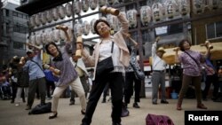 FILE - Elderly and middle-age people exercise with wooden dumbbells during a health promotion event to mark Japan's "Respect for the Aged Day" at a temple in Tokyo's Sugamo district, an area popular among the Japanese elderly, Sept. 21, 2015. 