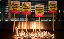 FILE - Signs and candles on a wall were placed at a vigil for the 39 smuggling victims found dead in a truck in an industrial park in England, outside the Home Office in London, Oct. 24, 2019.