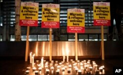 FILE - Signs and candles on a wall were placed at a vigil for the 39 smuggling victims found dead in a truck in an industrial park in England, outside the Home Office in London, Oct. 24, 2019.