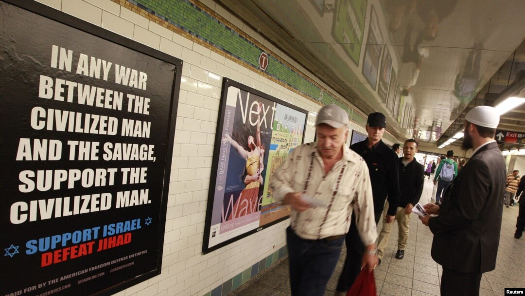 Cyrus McGoldrick, a member of the Council on American-Islamic Relations, talks to commuters as they walk by an advertisement that reads "Support Israel/Defeat Jihad" in the Times Square subway station in New York, September 24, 2012.