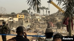 People gather near damaged buildings following a blast in Ibadan, Nigeria, January 17, 2024.