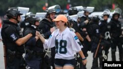 یکی از تماشاچیان بازی فوتبال آمریکایی در شارلوت پس از ترک استادیوم با ماموران پلیس ضد شورش صحبت می کند