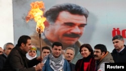 Selahattin Demirtas (front C), co-chairman of the pro-Kurdish Peace and Democracy Party (BDP), lights a traditional Newroz fire during a rally to celebrate the spring festival of Newroz - with a picture of imprisoned PKK leader Abdullah Ocalan seen in the