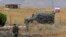 Syrian army soldier stands guard as Russian military police vehicle passes by near the town of Alhureyeh, Aug. 14, 2018. 