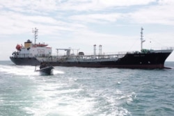 Dalam foto tak bertanggal yang dirilis Angkatan Laut ini, sebuah kapal angkatan laut berlayar melewati kapal tanker MT Zodiac Star berbendera Panama yang berlabuh di perairan Kepulauan Riau. (Foto: AP)