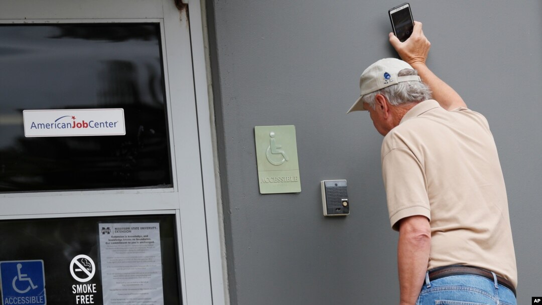 John Poe, a small business owner, speaks to an unseen state worker through an intercom speaker system at this state WIN job center in Canton,April 29, 2020. 