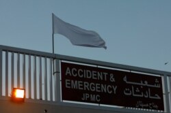 FILE - A white flag, part of a campaign to honor the doctors, nurses and paramedics fighting against the coronavirus disease, flutters on the Accident & Emergency building of the Jinnah Postgraduate Medical Centre in Karachi, March 27, 2020.