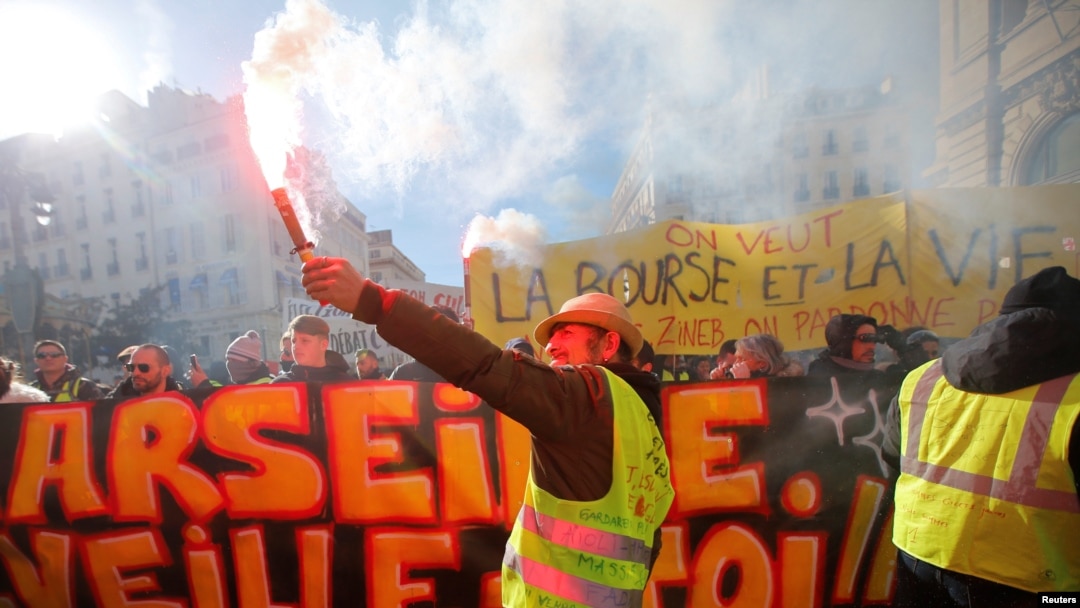 A protester wearing a yellow vest holds a flare as he takes part in a demonstration of the "yellow vests" movement in Marseille, France, January 26, 2019. 