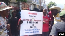 Protesters in Port-au-Prince, Haiti hold a poster demanding the US stop propping up the country's president during a protest, Friday, Oct. 4, 2019. (Photo: Matiado Vilme / VOA Creole) 