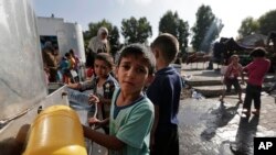 Displaced Palestinian children collect water at the Abu Hussein U.N. school in Jebaliya refugee camp, northern Gaza Strip, on July 30, 2014. It had been hit by artillery shells earlier in the day. 