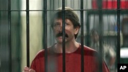 Terduga penyelundup senjata Rusia Viktor Bout mendengarkan pertanyaan wartawan dari dalam sel di pengadilan pidana di Bangkok, Senin, 4 Oktober 2010. (AP /Apicart Weerawong) 