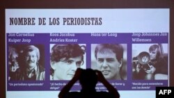 Un miembro de una organización de derechos humanos toma una fotografía de una pantalla que muestra a cuatro periodistas holandeses asesinados por las Fuerzas Armadas de El Salvador en el 39 aniversario del crimen, en San Salvador, el 17 de marzo de 2021.