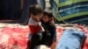 An internally displaced boy from northern provinces, who fled from his home due the fighting between Taliban and Afghan security forces, is comforted by his sister in a public park that they use as shelter in Kabul, Afghanistan.
