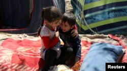 An internally displaced boy from northern provinces, who fled from his home due the fighting between Taliban and Afghan security forces, is comforted by his sister in a public park that they use as shelter in Kabul, Afghanistan.