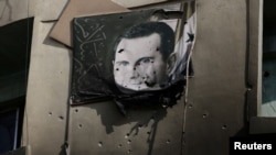 (FILE) A picture of Bashar al-Assad, damaged by bullets, hangs on the wall of a burnt building of Criminal Security department in Damascus, Syria, December 20, 2024.