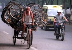 Un repartidor chino transporta una carga de bicicletas de producción local en la parte trasera de su triciclo, el 18 de julio de 1996.
