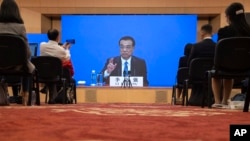 Chinese Premier Li Keqiang speaks on screen during a press conference by video conferencing at the end of the National People's Congress in Beijing on Thursday, May 28, 2020. 