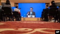 Chinese Premier Li Keqiang speaks on screen during a press conference by video conferencing at the end of the National People's Congress in Beijing on Thursday, May 28, 2020. 