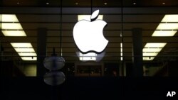 FILE - An illuminated Apple logo is seen at a store in Munich, Germany, Dec. 16, 2020.