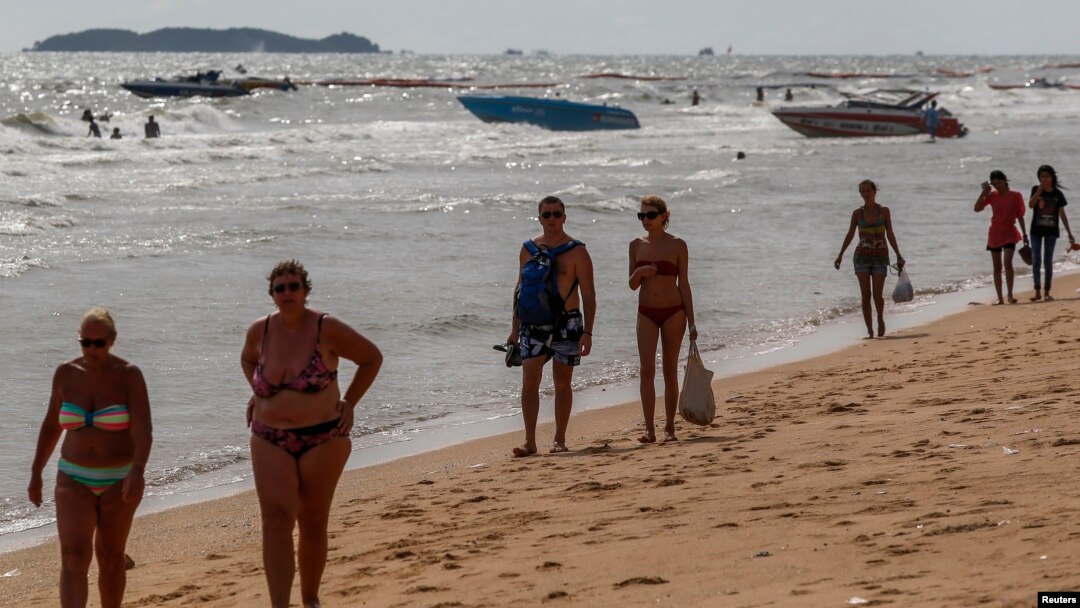 Tourists walk on a beach in Pattaya, June 6, 2014.