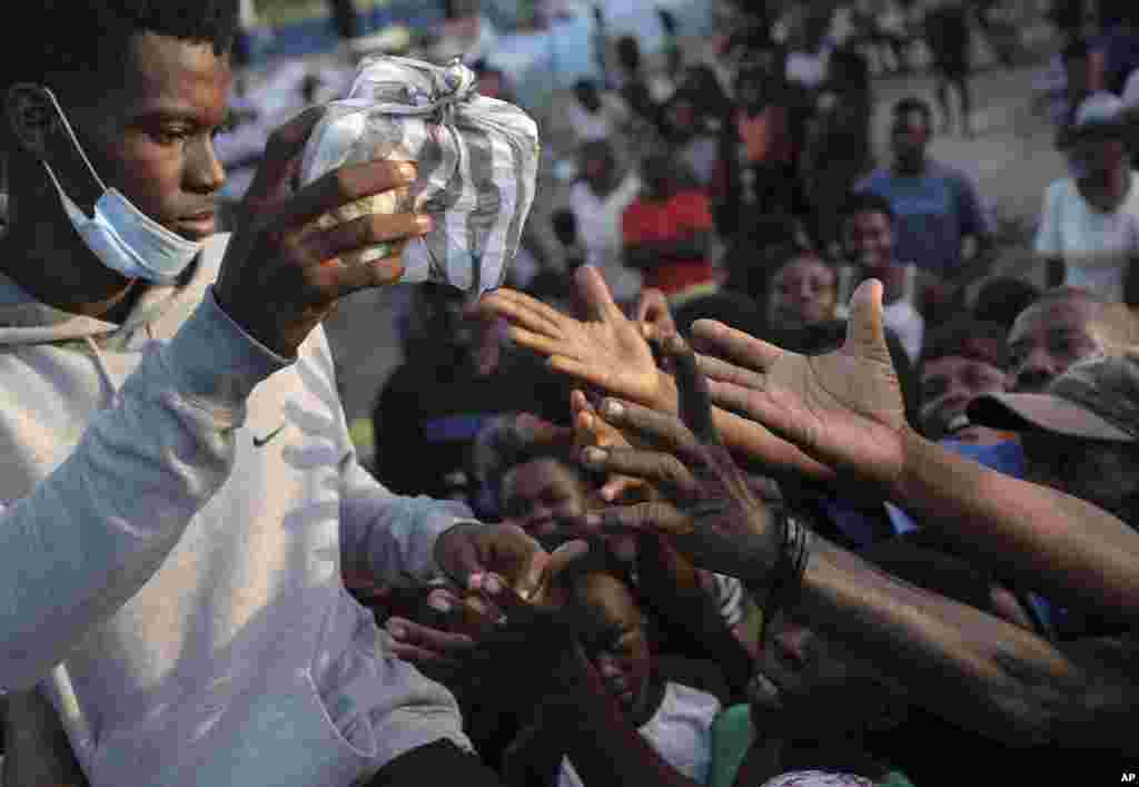 Earthquake victims try to grab a food bag during a food distribution in Les Cayes, Haiti, Aug. 21, 2021, seven days after a 7.2 magnitude earthquake hit the area.