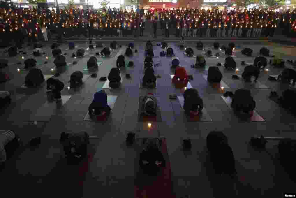 People pray during a candlelight vigil to commemorate the victims of capsized passenger ferry Sewol and to wish for the safe return of missing passengers, in Ansan, Korea, April 23, 2014.