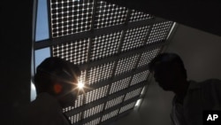 Officials pose in the backdrop of an atrium roof fitted with glass solar cells at The Energy and Resources Institute, TERI, office during the inauguration of the Smart Mini-Grid, in Gurgaon, India, Friday, July 1, 2011. A Smart Mini-Grid is an intelligent