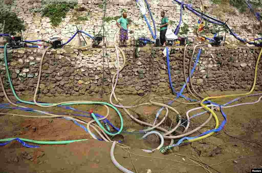 Habitantes usam bombas para coletar água de uma lagoa parcialmente seca em Penglai, província de Shandong, China. A Província tem sofrido uma seca grave desde a primavera.