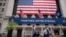 People wearing protective face masks pass the New York Stock Exchange, as employees arrive for the partial reopening of the trading floor, May 26, 2020.