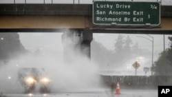 Un automóvil avanza en medio de una calle inundada el domingo 24 de octubre de 2021 en la carretera 101 de Corte Madera, California. (AP Foto / Ethan Swope)