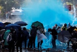 Protesters are sprayed with blue liquid from water cannon during clashes with police outside Hong Kong Polytechnic University (PolyU) in Hong Kong, Nov. 17, 2019.