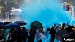 Protesters are sprayed with blue liquid from water cannon during clashes with police outside Hong Kong Polytechnic University in Hong Kong, Nov. 17, 2019.
