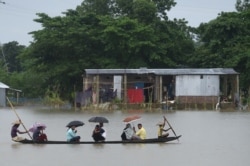 People ride on a boat through flooded waters in Sunamgong, Bangladesh, July 14, 2020.
